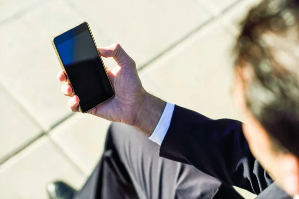 Businessman using his smartphone in the street — Stock Photo, Image