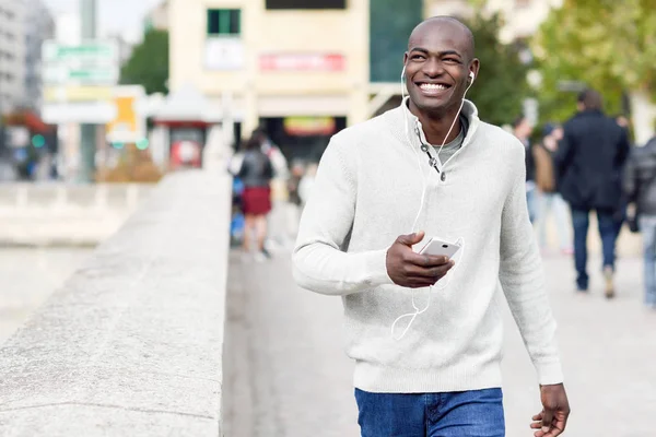 Чорний молодий чоловік зі смартфоном в руці в міському фоні — стокове фото