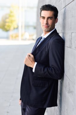 Genç işadamı giyiyor Mavi takım elbise ve kravat kentsel arka planda