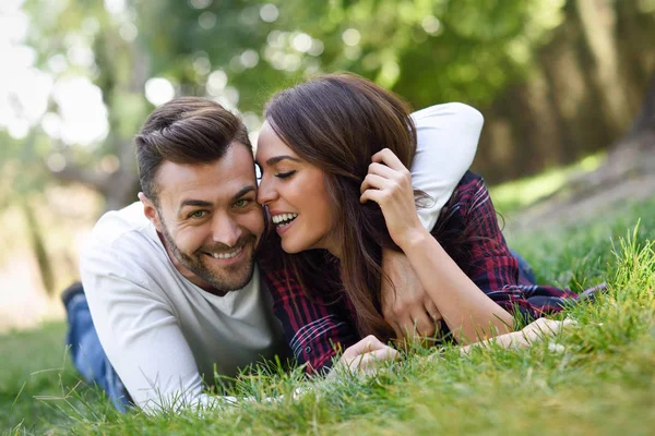 Belo jovem casal que coloca na grama em um parque urbano . — Fotografia de Stock