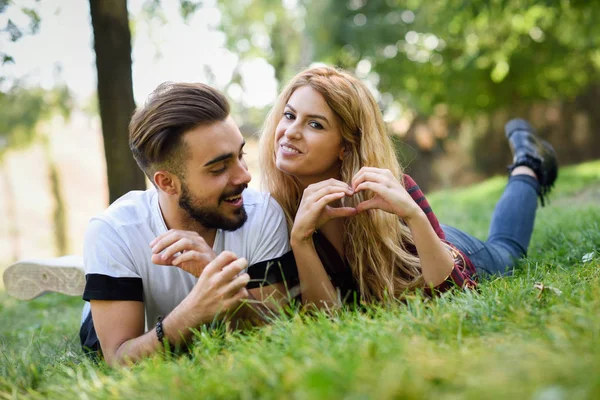 Beautiful young couple laying on grass in an urban park. — Stock Photo, Image