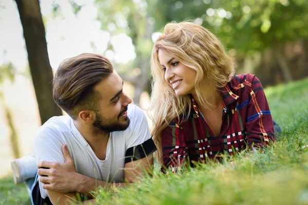 Schönes junges Paar liegt auf Gras in einem Stadtpark. — Stockfoto