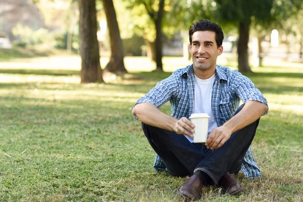 Uomo che beve caffè per andare in un parco urbano — Foto Stock