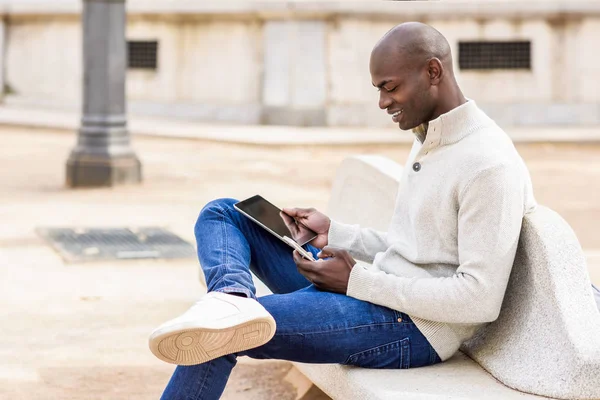 Schwarzer junger Mann blickt auf Tablet-Computer und Smartphone — Stockfoto