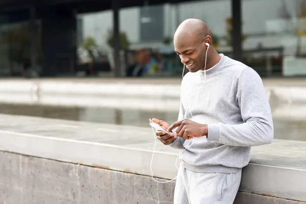 Attraente uomo nero che ascolta musica con le cuffie in città — Foto Stock