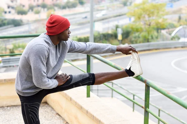 Schwarzer macht Stretching, bevor er im städtischen Hintergrund läuft — Stockfoto