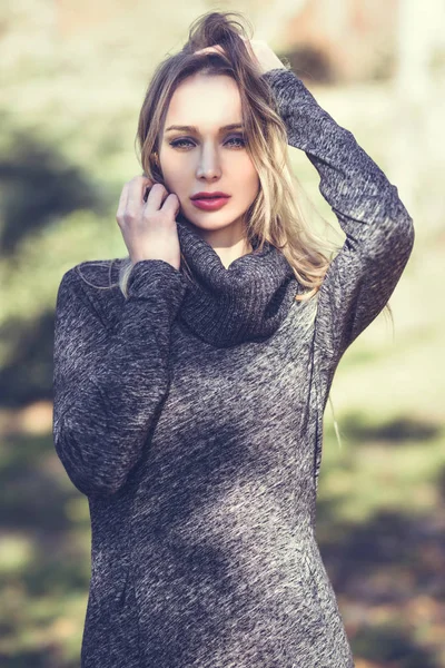 Jonge blonde vrouw die permanent in een park met herfst kleuren — Stockfoto