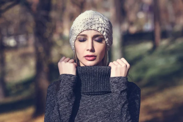 Jonge blonde vrouw die permanent in een park met herfst kleuren — Stockfoto