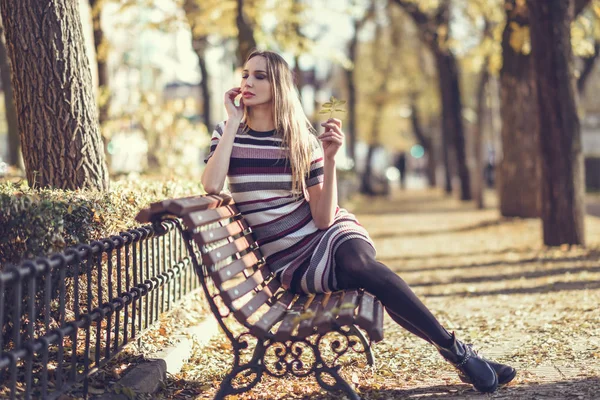 公園のベンチに座っている若いブロンドの女性 — ストック写真