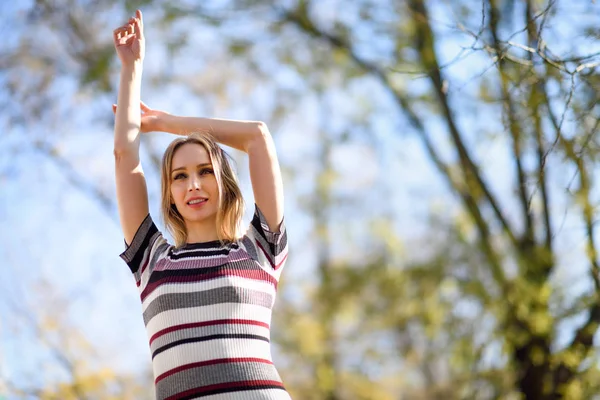 Young blonde woman standing in the street raising her arms — Stock Photo, Image