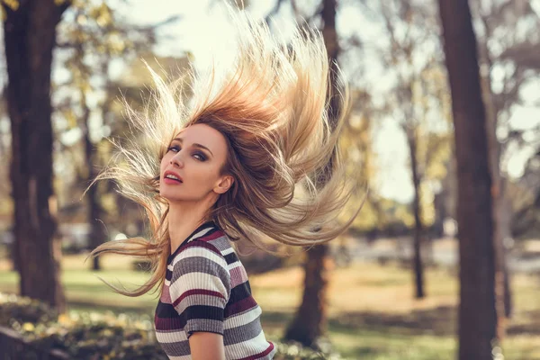 Молодая блондинка, стоящая на улице и двигающая волосами — стоковое фото