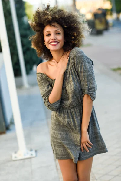 Joven mujer negra con peinado afro sonriendo en el fondo urbano —  Fotos de Stock