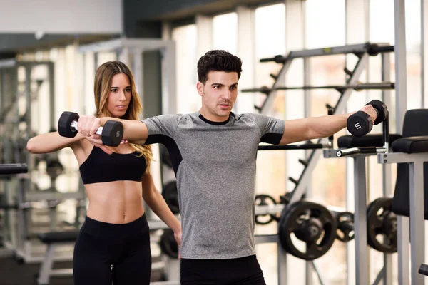 Personal Trainer hilft einem jungen Mann beim Heben von Gewichten — Stockfoto