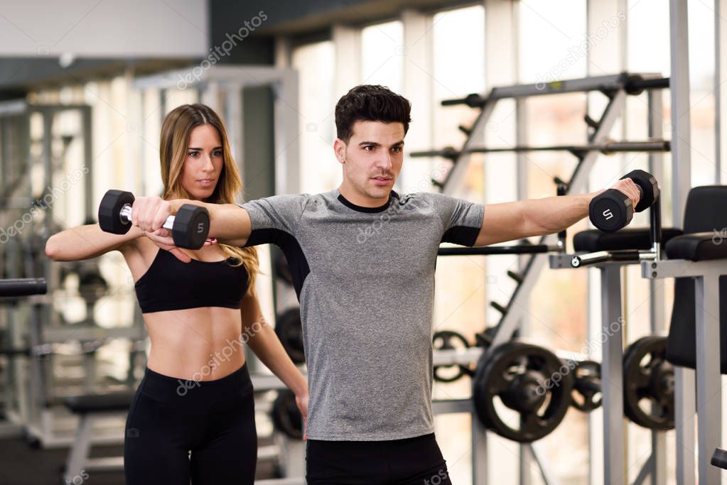 Personal trainer helping a young man lift weights — Stock