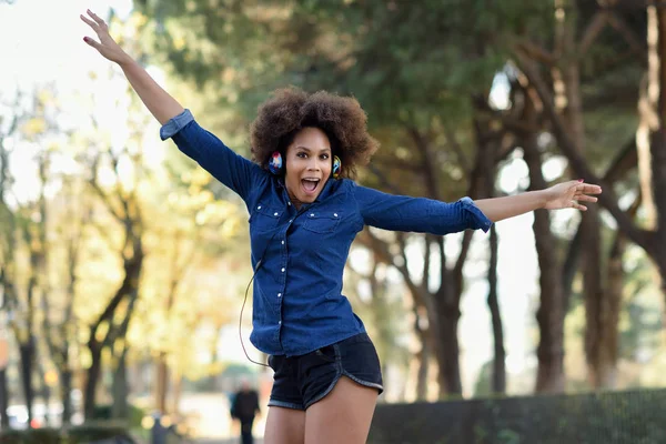 Jovem mulher negra com penteado afro pulando em backgroun urbano — Fotografia de Stock