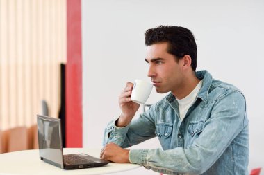 İyi görünümlü bir adam kahve barda oturmuş kot gömlek giymiş