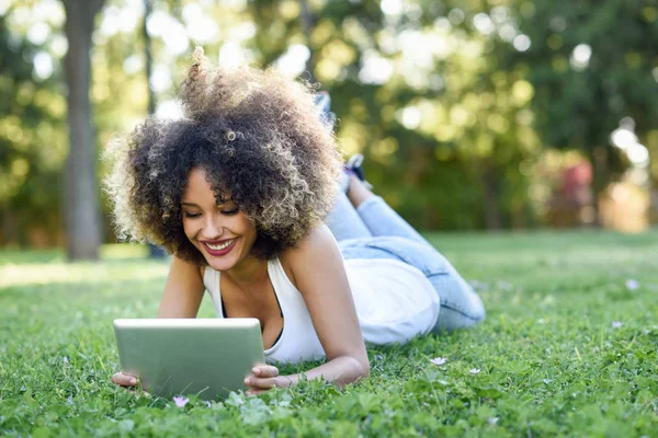 Mujer mixta con peinado afro mirando su tableta —  Fotos de Stock