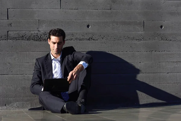 Empresario usando un ordenador portátil sentado en la calle — Foto de Stock