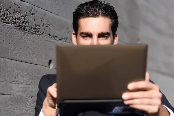 Businessman using a laptop computer sitting in the street — Stock Photo, Image