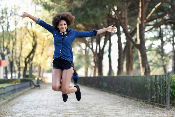 Jovem mulher negra com penteado afro pulando em backgroun urbano — Fotografia de Stock