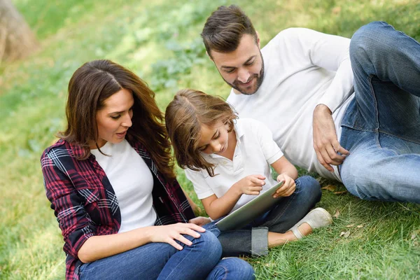 Счастливая семья в городском парке играет с планшетным компьютером — стоковое фото