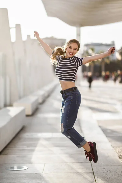 Mujer rubia divertida saltando en el fondo urbano . —  Fotos de Stock