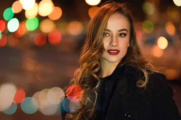Woman wearing black jacket in the street with defocused lights — Stock Photo, Image