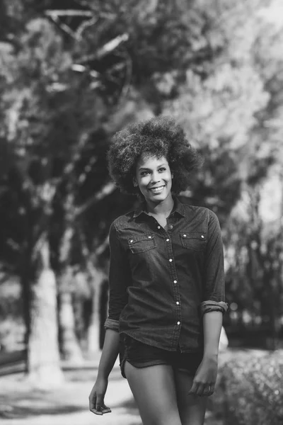 Giovane donna nera con acconciatura afro a piedi nel parco urbano — Foto Stock