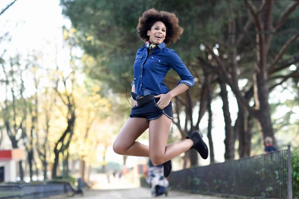 Junge schwarze Frau mit Afro-Frisur springt im urbanen Hintergrund — Stockfoto