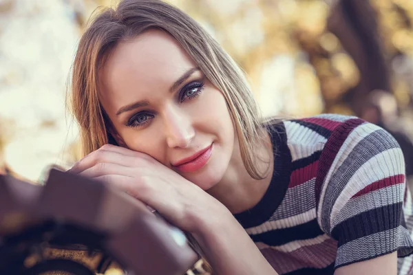 Jeune femme blonde assise sur un banc d'un parc — Photo