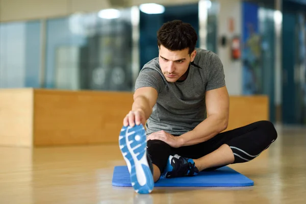 체육관에서 자신의 다리를 스트레칭 하는 젊은 남자. — 스톡 사진