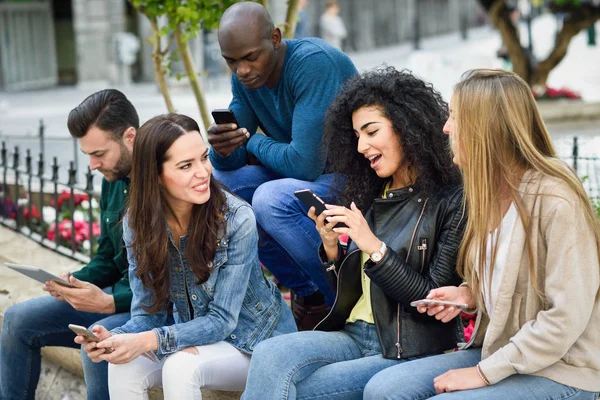 Jeunes multiethniques utilisant des smartphones et des tablettes — Photo