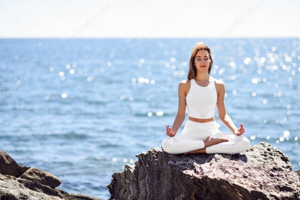 Young woman doing yoga in the beach