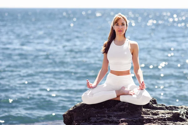 Mujer joven haciendo yoga en la playa vistiendo ropa blanca —  Fotos de Stock