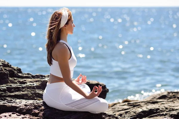 Mujer joven haciendo yoga en la playa vistiendo ropa blanca —  Fotos de Stock