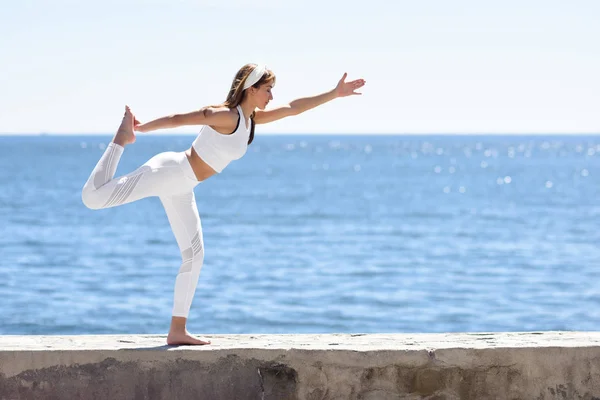 Genç kadın beyaz elbise giyen Beach yoga yaparken — Stok fotoğraf