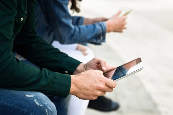 Jóvenes irreconocibles usando smartphone y tablet — Foto de Stock