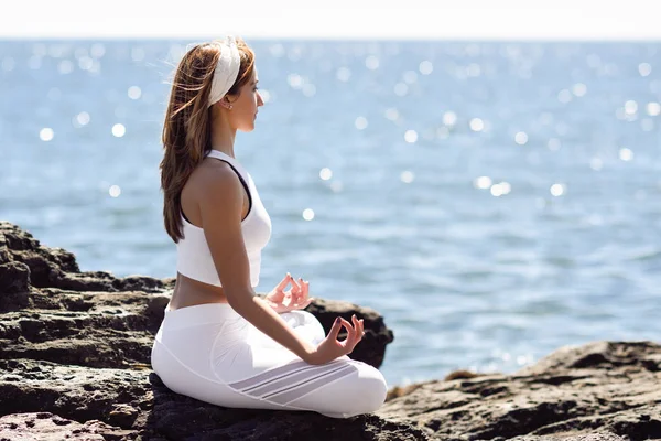 Young woman doing yoga in the beach wearing white clothes — Stock Photo, Image