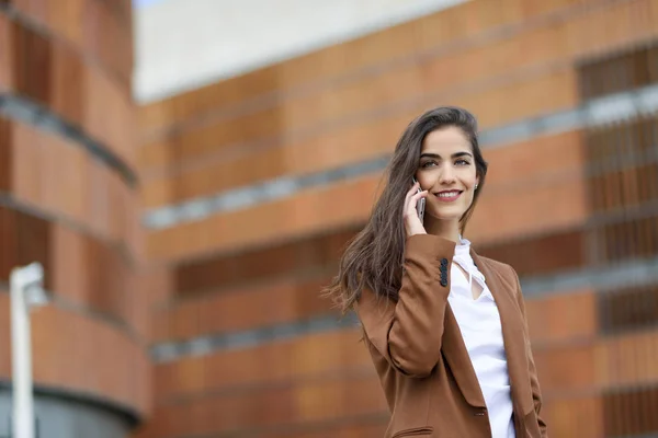 Jonge zakenvrouw in gesprek met een smartphone in stedelijke pagina — Stockfoto