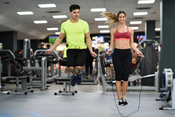 Homem e mulher treino com pulando corda no ginásio crossfit — Fotografia de Stock