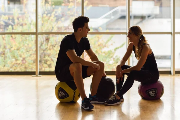 Man en vrouw zitten met fitballs in de sportschool. — Stockfoto