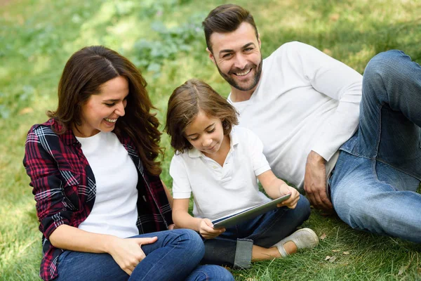 Une famille heureuse dans un parc urbain jouant avec une tablette — Photo