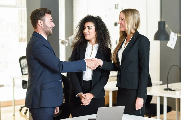 Kaukasische Männer und Frauen beim Händeschütteln im Anzug. — Stockfoto