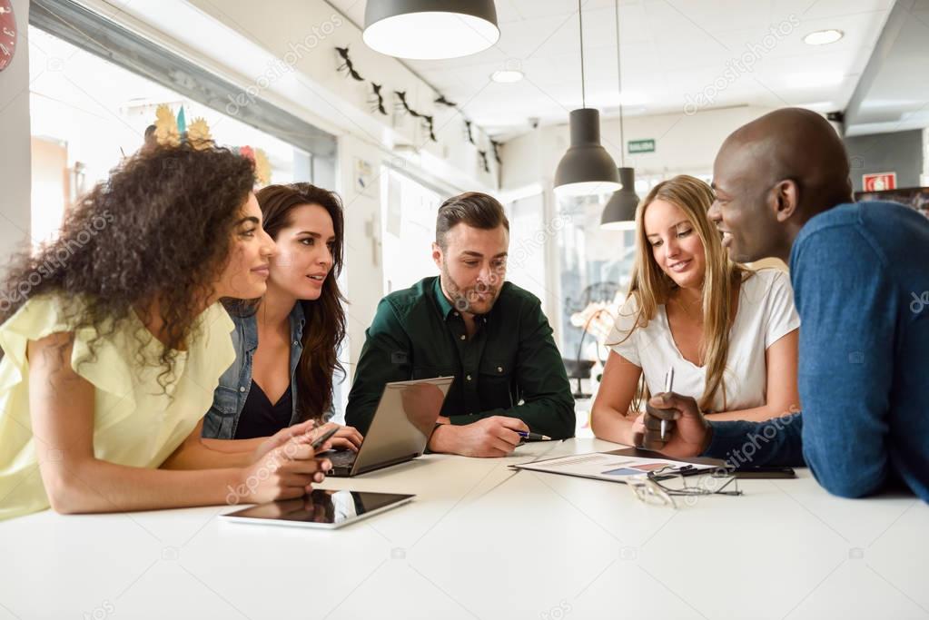 Multi-ethnic group of young people studying together on white de