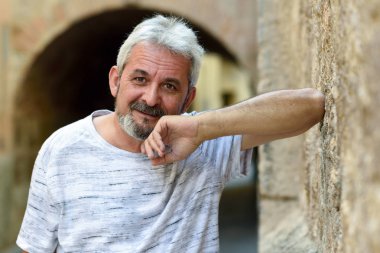 Olgun adam kamera kentsel arka planda bakarak gülen