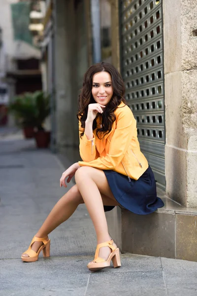 Ung brunett kvinna ler i urban bakgrund. — Stockfoto