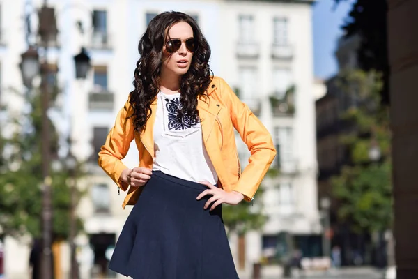 Jonge brunette vrouw met zonnebril op stedelijke achtergrond — Stockfoto