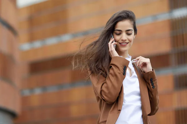 Jonge zakenvrouw in gesprek met een smartphone in stedelijke pagina — Stockfoto