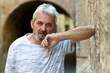 Olgun adam kentsel arka planda kamera bakıyor