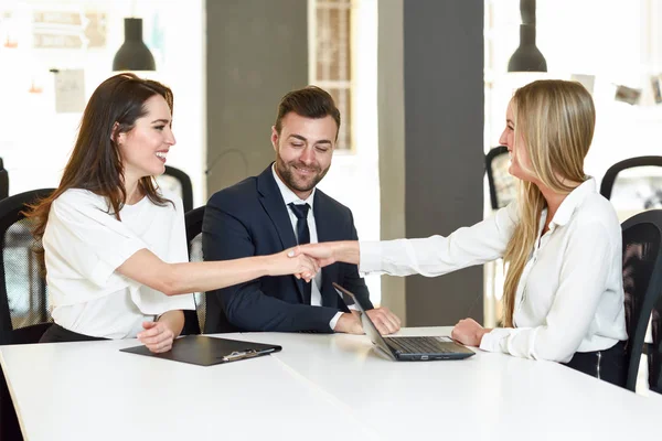 Leende unga par skakar hand med en försäkringsagent — Stockfoto